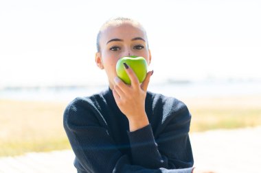 Dışarıda elinde elma tutan Faslı genç bir kız.