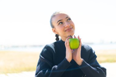 Dışarıda elinde elma tutan Faslı genç bir kız.
