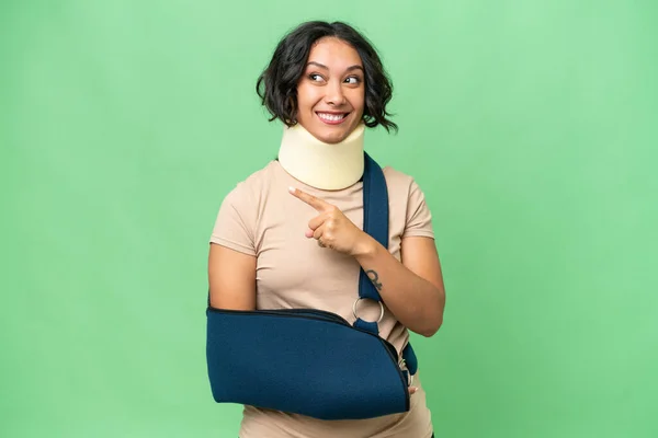 stock image Young argentinian woman wearing neck brace and sling over isolated background pointing up a great idea