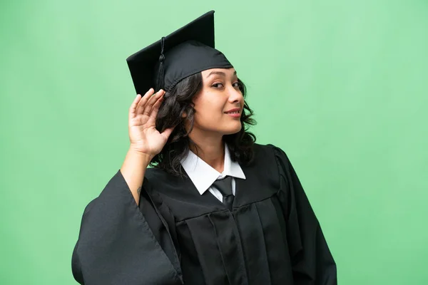 stock image Young university graduate Argentinian woman over isolated background listening to something by putting hand on the ear