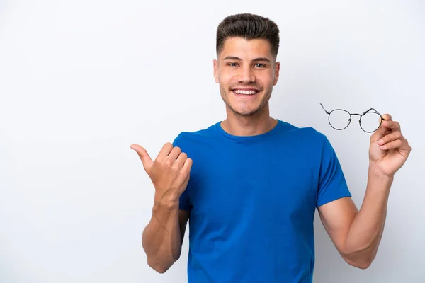 製品を提示するために側面を指す白い背景に隔離された眼鏡を保持若い白人男性 — ストック写真