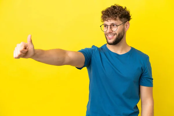 stock image Young handsome caucasian man isolated on yellow background giving a thumbs up gesture