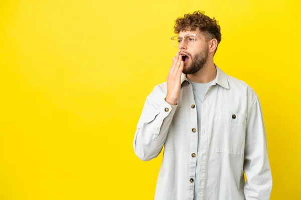 stock image Young handsome caucasian man isolated on yellow background yawning and covering wide open mouth with hand