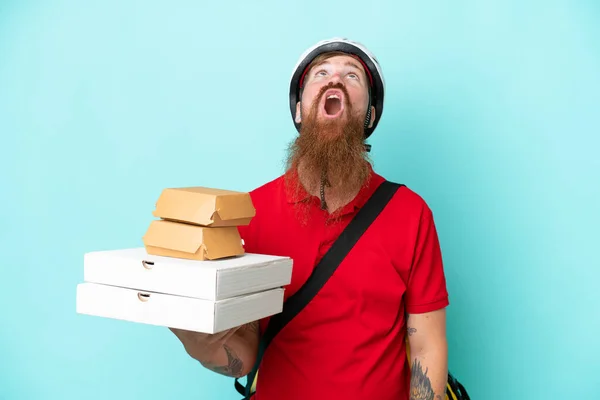 Dodavatel Drží Pizzy Hamburgery Izolované Modrém Pozadí Vzhlíží Překvapeným Výrazem — Stock fotografie