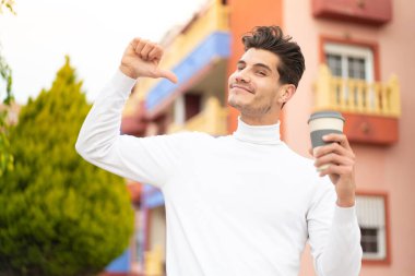 Kafkasyalı genç bir adam açık havada kahvesini yudumlarken gururlu ve kendini beğenmiş.