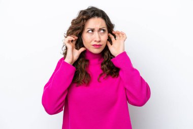 Beyaz arka planda izole edilmiş genç beyaz kadın hayal kırıklığına uğramış ve kulaklarını kapatmış.