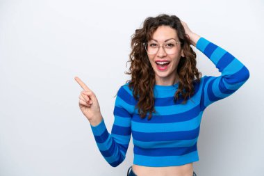 Beyaz arka planda izole edilmiş genç beyaz kadın şaşırmış ve işaret ediyor.