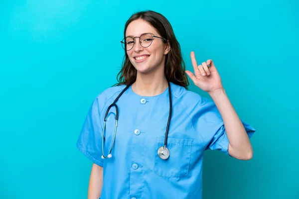 Junge Chirurgin Ärztin Isoliert Auf Blauem Hintergrund Zeigt Und Hebt — Stockfoto
