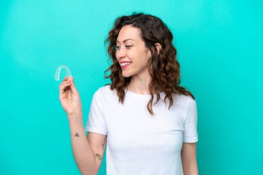 Young caucasian woman holding a envisaging isolated on blue background with happy expression