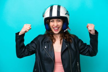 Young caucasian woman with a motorcycle helmet isolated on blue background doing strong gesture