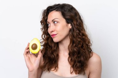 Beyaz arka planda avakado tutan beyaz bir kadın. Portreyi kapat