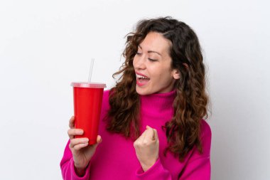 Young caucasian woman drinking soda isolated on white background celebrating a victory