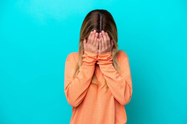 Genç Uruguaylı kadın yorgun ve hasta bir ifadeyle mavi arka planda izole edilmiş.