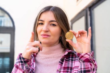 Genç ve güzel Romen kadın elinde Bitcoin ile dışarıda