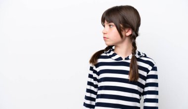 Beyaz arka planda izole edilmiş küçük beyaz kız yan tarafa bakıyor.