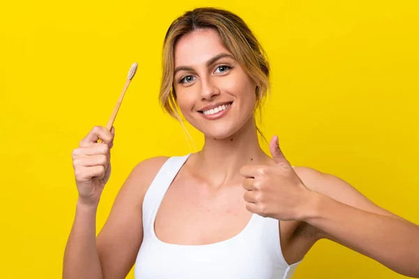 Młoda Urugwajska Kobieta Myje Zęby Żółtym Tle Kciukami Górze Stało — Zdjęcie stockowe