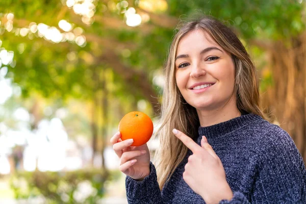 Fiatal Csinos Román Kezében Egy Narancs Szabadban Rámutatva Hogy — Stock Fotó