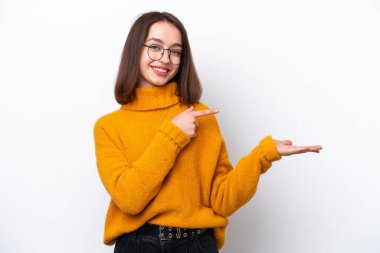 Beyaz arka planda izole edilmiş genç Ukraynalı bir kadın bir ilan vermek için avucunun içinde hayali bir kopyalama alanı tutuyor.