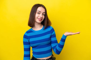 Sarı arka planda izole edilmiş genç Ukraynalı bir kadın gülümseyerek bir fikir sunuyor.