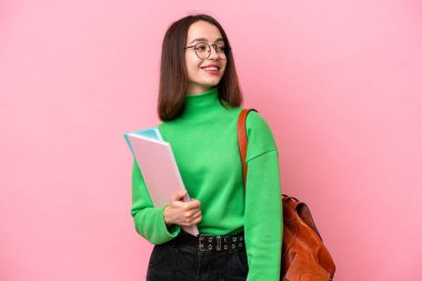 Genç öğrenci Ukraynalı kadın pembe arka planda izole edilmiş. Yan tarafa bakıyor ve gülümsüyor.