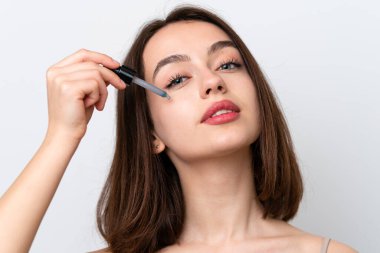 Young Ukrainian woman isolated on white background holding a serum. Close up portrait