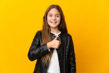 Child over isolated yellow background giving a thumbs up gesture