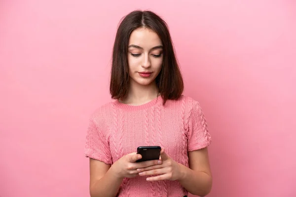 stock image Young Ukrainian woman isolated on pink background using mobile phone