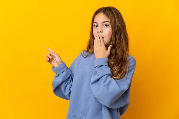 stock image Child over isolated yellow background with surprise expression while pointing side