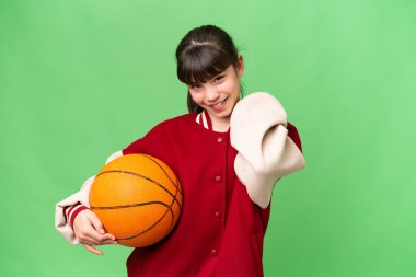 İzole edilmiş arka planda basketbol oynayan küçük beyaz kız gülüyor.