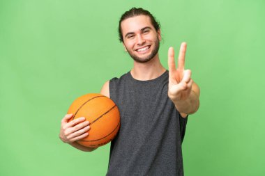 İzole edilmiş arka planda genç basketbolcu gülümsüyor ve zafer işareti gösteriyor.