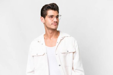 Beyaz arka planda beyaz tenli yakışıklı bir adam yan tarafa bakıyor.