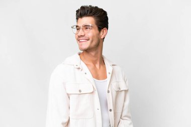 Young handsome caucasian man over isolated white background looking to the side and smiling