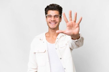 İzole edilmiş beyaz arka planda genç beyaz adam parmaklarıyla beşi sayıyor.