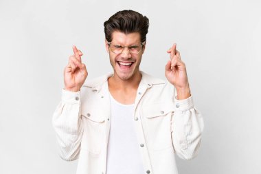 Young handsome caucasian man over isolated white background with fingers crossing