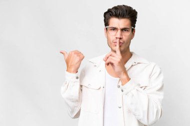 İzole edilmiş beyaz arka planda genç, yakışıklı beyaz bir adam. Yan tarafı işaret ediyor ve sessiz hareketler yapıyor.