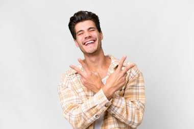 Beyaz arka planda yaşayan yakışıklı beyaz adam gülümsüyor ve zafer işareti gösteriyor.