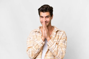 Young handsome caucasian man over isolated white background keeps palm together. Person asks for something