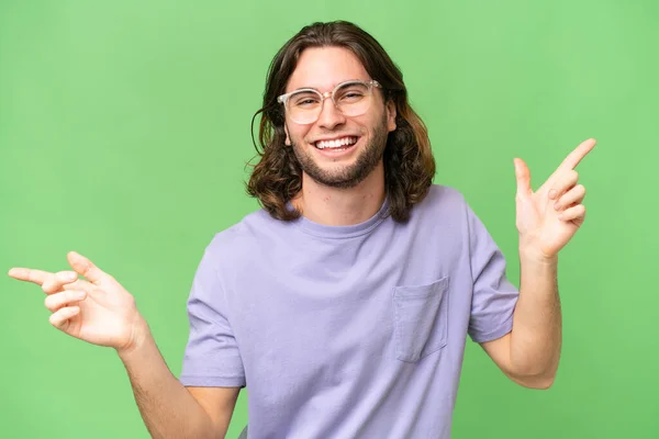 Jonge Knappe Man Geïsoleerde Achtergrond Wijzend Vinger Naar Lateralen Gelukkig — Stockfoto