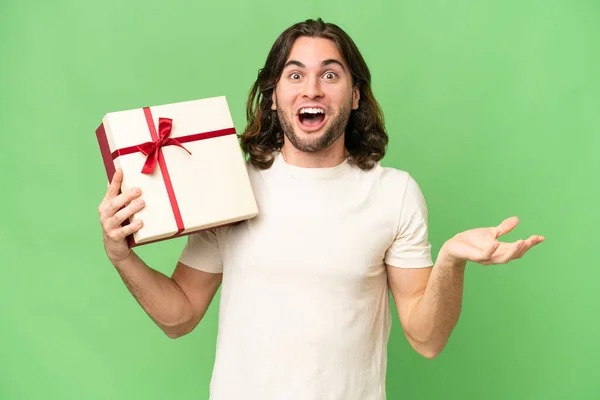 Young Handsome Man Holding Gift Isolated Background Shocked Facial Expression — Stock Photo, Image