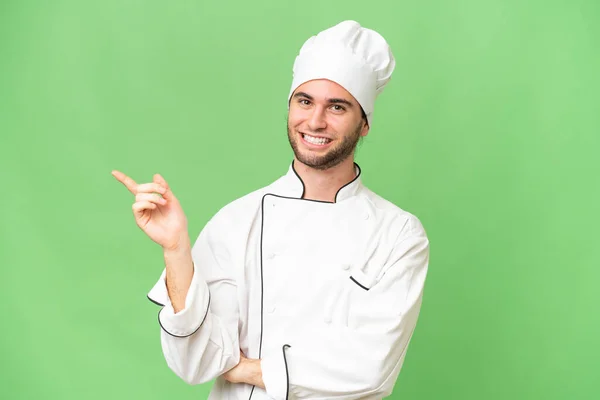 Mladý Pohledný Kuchař Muž Přes Izolované Pozadí Ukazující Prstem Stranu — Stock fotografie