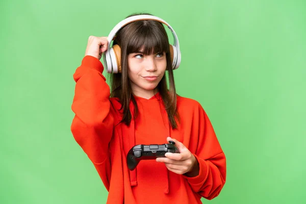stock image Little caucasian girl playing with a video game controller over isolated background having doubts and thinking