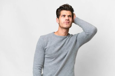 Young handsome caucasian man over isolated white background having doubts and with confuse face expression