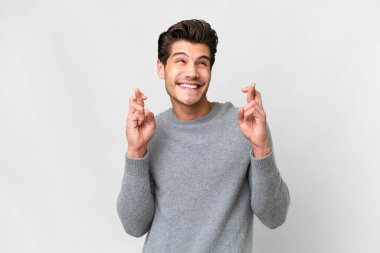 Young handsome caucasian man over isolated white background with fingers crossing