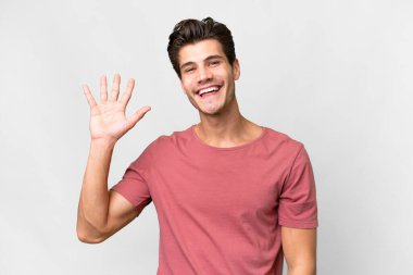 Young handsome caucasian man over isolated white background saluting with hand with happy expression