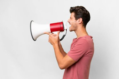 Soyutlanmış beyaz arka planda genç, yakışıklı beyaz bir adam megafondan bağırıyor.