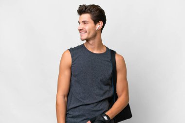 İzole edilmiş beyaz arka planda spor çantalı beyaz tenli genç bir adam.