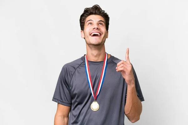 stock image Young caucasian man with medals over isolated white background pointing up and surprised