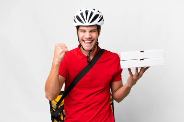 Pizza delivery man with work uniform picking up pizza boxes over isolated white background celebrating a victory