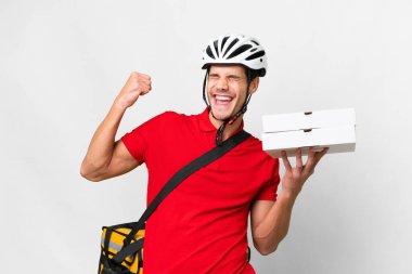 Pizza delivery man with work uniform picking up pizza boxes over isolated white background celebrating a victory