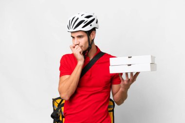 Pizza delivery man with work uniform picking up pizza boxes over isolated white background having doubts